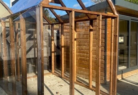 "Timber-framed greenhouse with crystal-clear polycarbonate glazing, showcasing a durable and elegant structure that maximizes natural light for optimal plant growth."