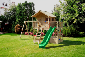 Fungoo wooden treehouse play centre featuring deck, slide, rock climbing wall, and swings in an Irish family garden